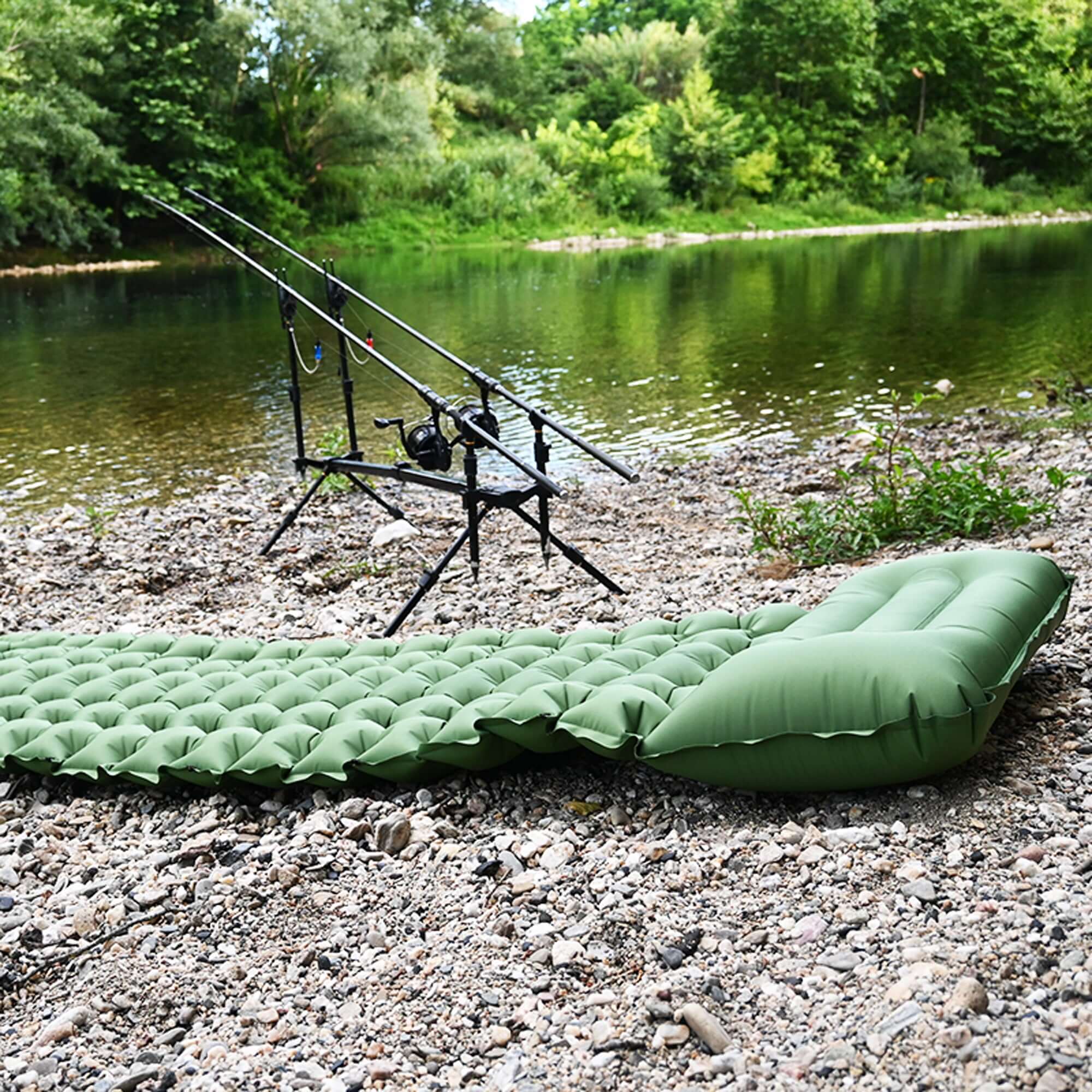 Inflatable camping mattress by a riverside with fishing rods, ideal for roof tents, featuring comfort and quick setup.