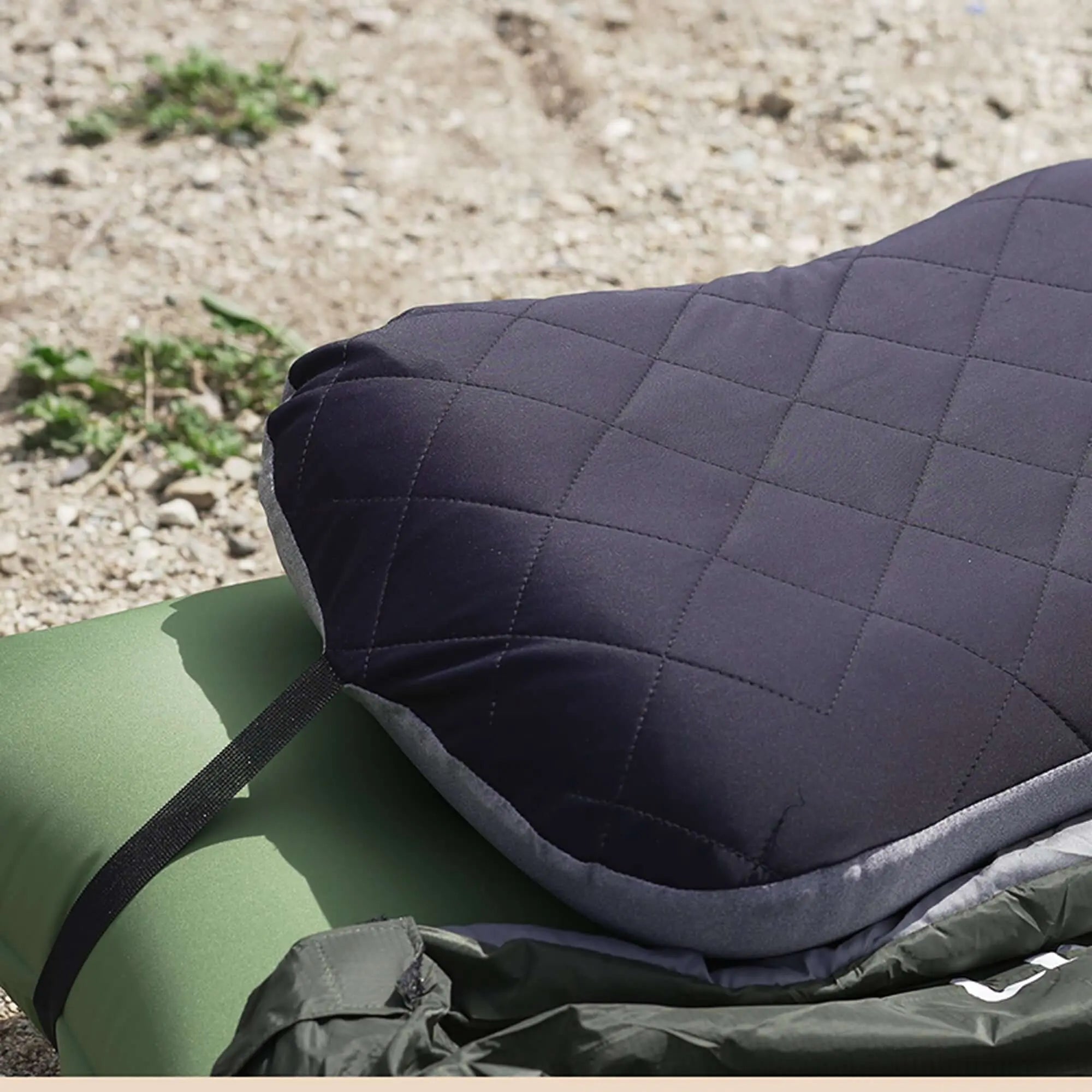 Ultralight inflatable camping pillow on ground next to a green sleeping mat, perfect for comfortable outdoor adventures.