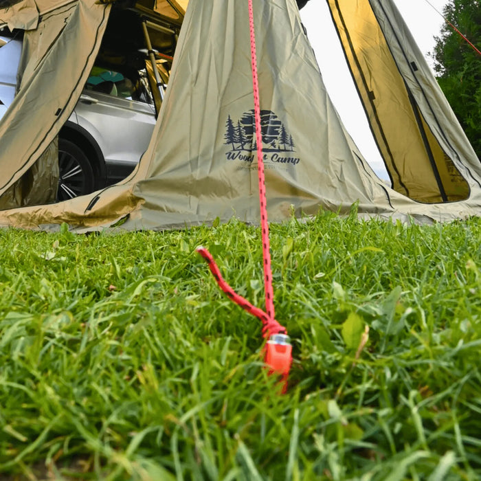 Tente de camping fixée avec des sardines de 20 cm pour une installation stable sur l'herbe.