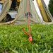 Tente de camping fixée avec des sardines de 20 cm pour une installation stable sur l'herbe.