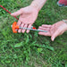 Une personne tenant un piquet de tente orange de 20 cm pour une installation rapide et facile au sol sur de l'herbe.