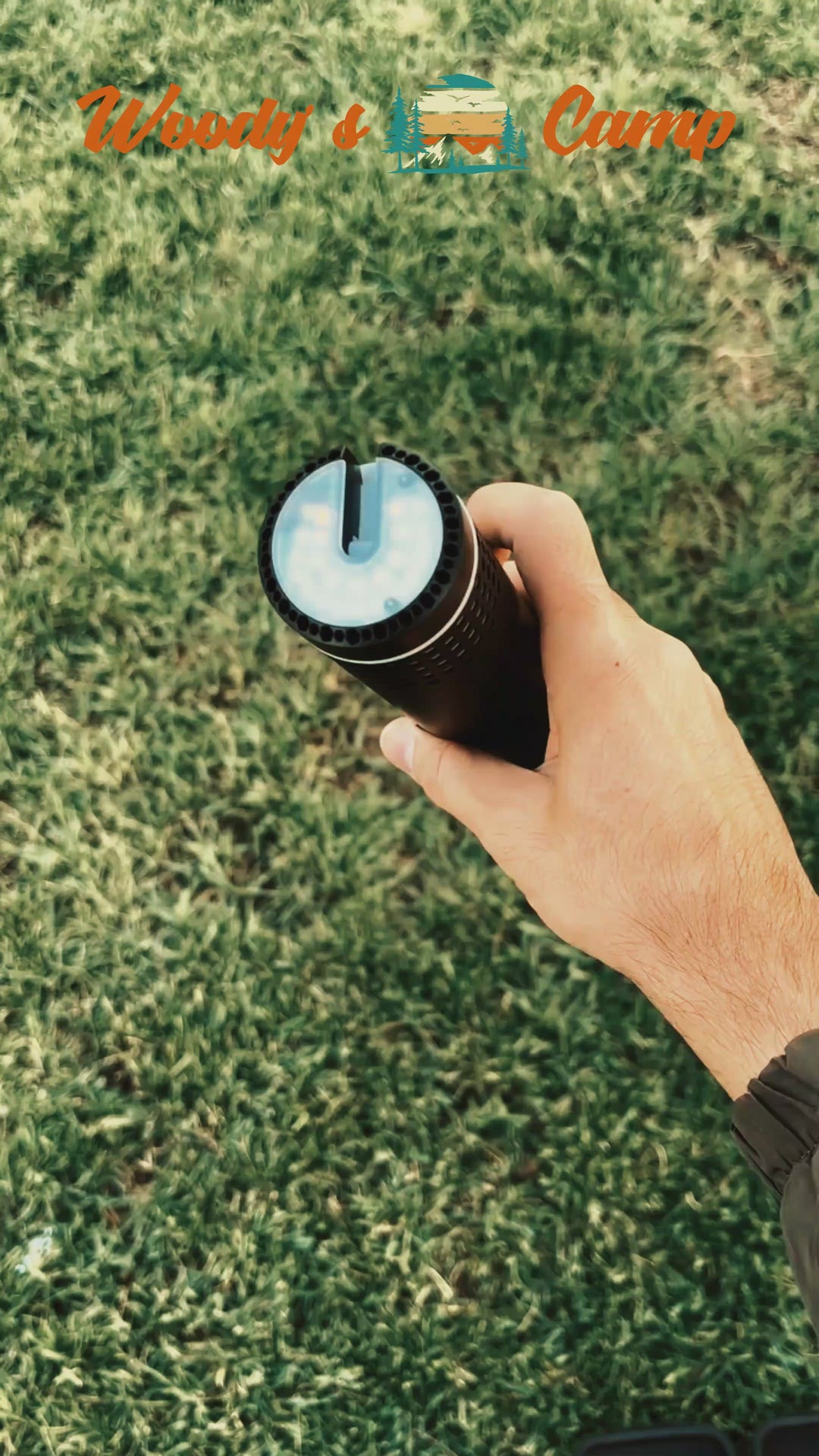 Person holding a portable telescopic LED camping lamp outdoors.