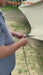 Person using a Serre-Corde Anti-Vent with pulleys to secure a tent in an outdoor camping setting.