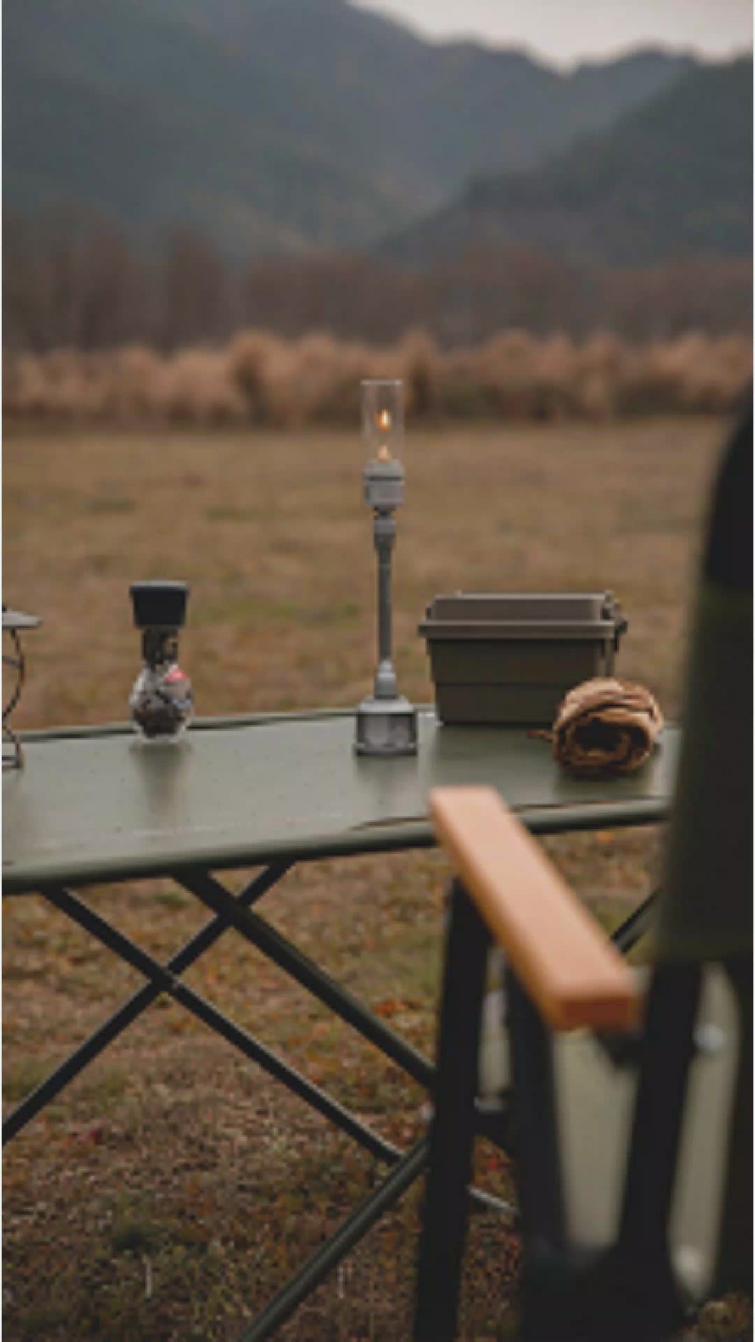 Outdoor camping setup with a rechargeable gas lantern on a table, surrounded by nature, creating a warm and inviting atmosphere.