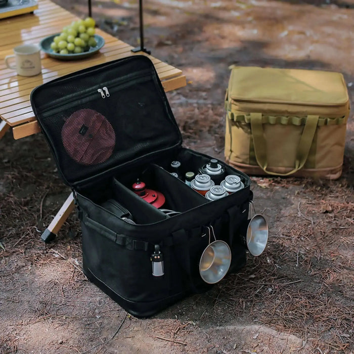 Boîte de transport pliable avec armature métallique pour ranger les équipements de camping sur le sol de la forêt, ouverte et remplie.