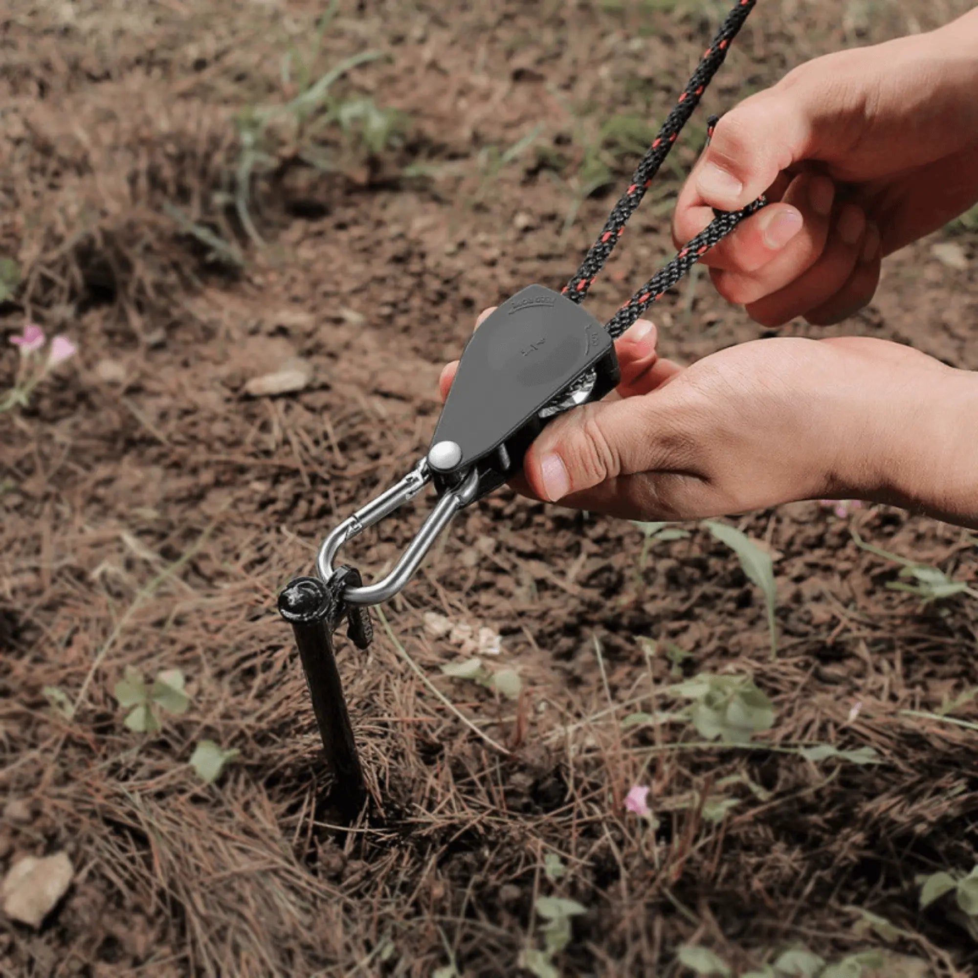 Using a windproof rope clamp with pulley for secure tent anchoring during camping.