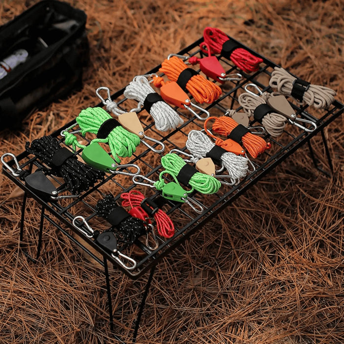Ensemble de cordes de camping colorées avec système de poulie anti-vent sur une table d'exposition, idéal pour la stabilité des tentes et du matériel de plein air.