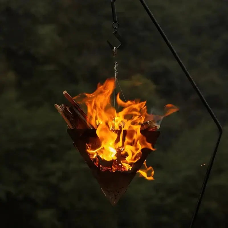 Triangular camping fire pit with burning wood, stainless steel frame, lightweight and portable for outdoor use.