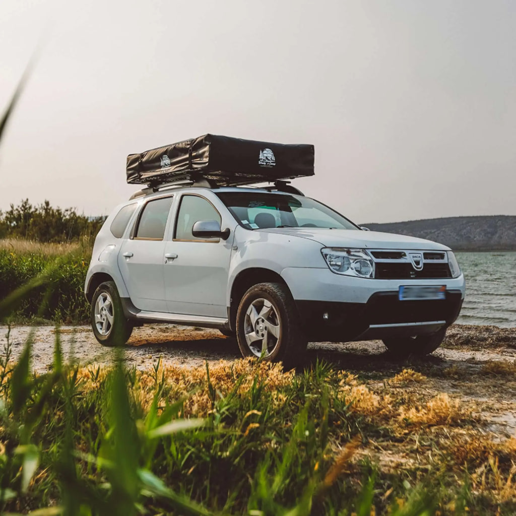 SUV avec une couverture de tente de toit stationné au bord d'un lac, mettant en avant une housse en PVC résistante aux intempéries pour tentes sur toit de 3 et 5 places.