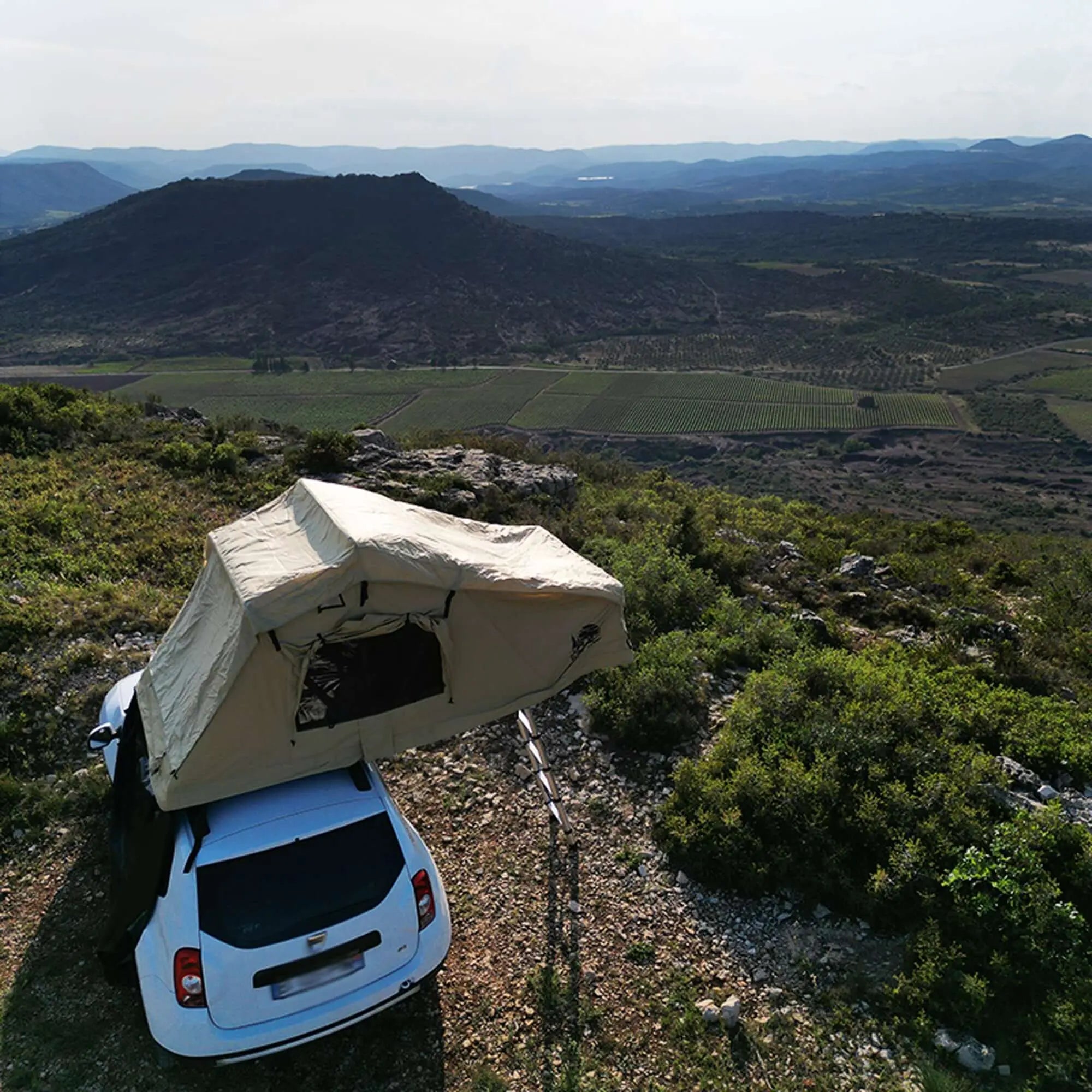 Tente de toit souple pour 2-3 personnes installée sur une voiture, offrant une vue panoramique sur la nature environnante.