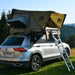 Voiture avec tente rigide sur le toit et annexe dans un cadre extérieur, idéale pour des aventures en camping.