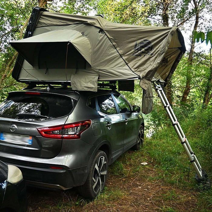 Voiture avec une tente de toit rigide pour trois personnes et un auvent installé dans une forêt, montrant les détails de la structure de la tente et l'accès par échelle.