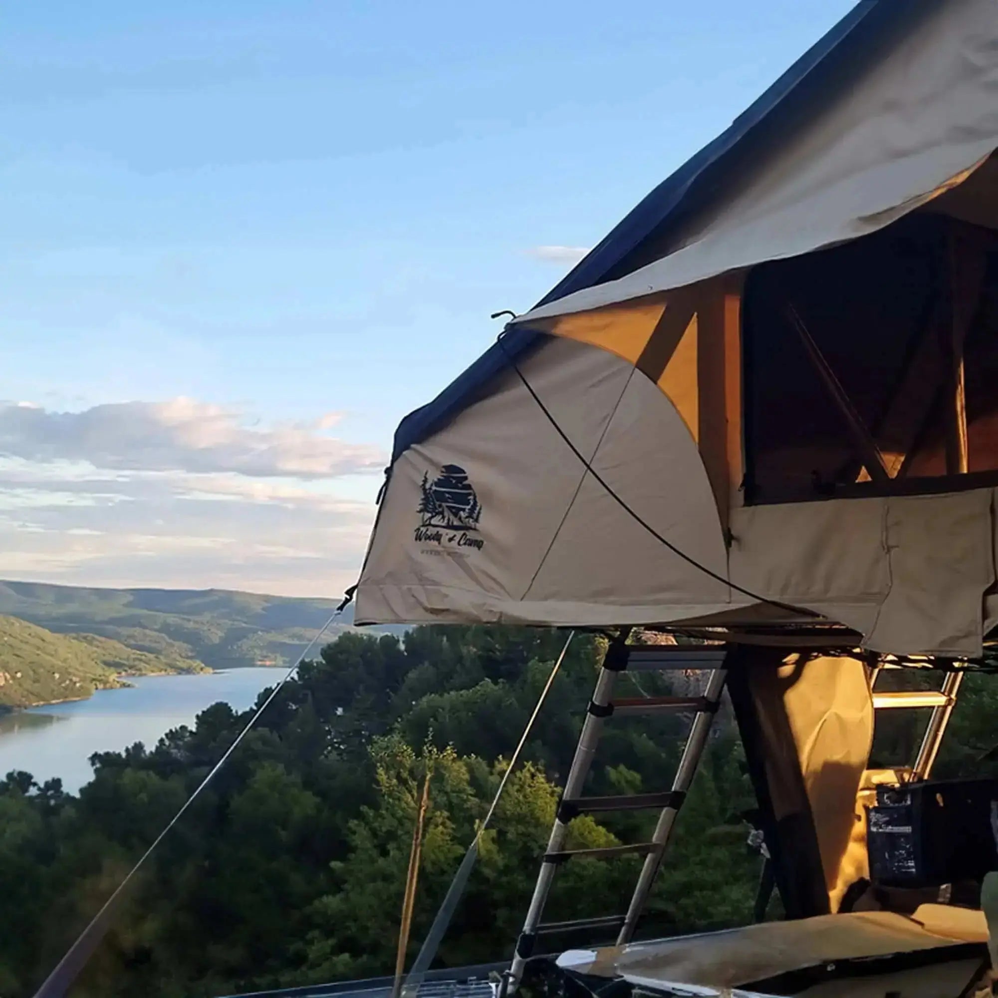Rooftop tent set up in scenic landscape, beige with black roof, designed for 4-5 people, available for 2025 pre-order.