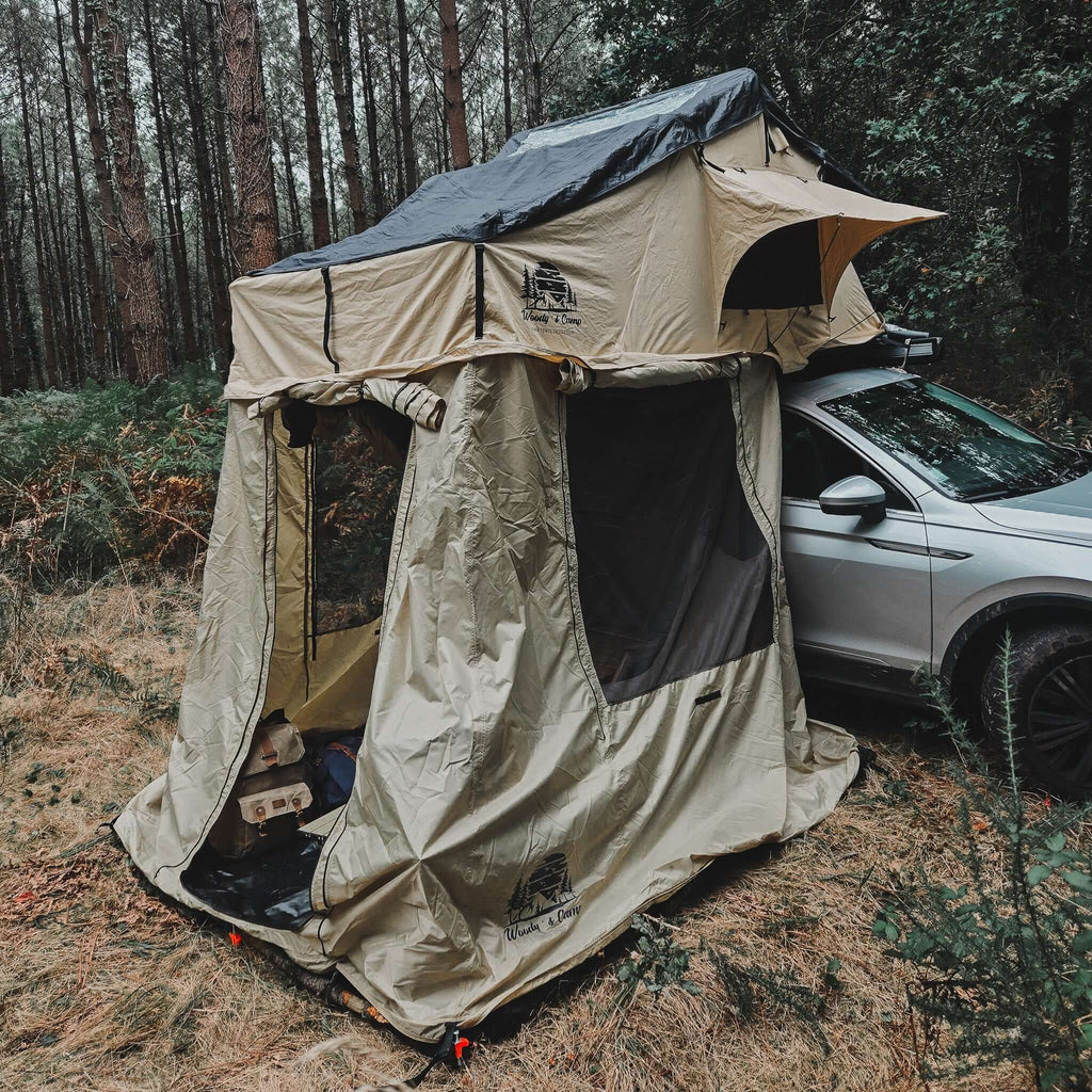 Tente de toit souple 3 places avec annexe installée sur voiture dans la forêt, idéale pour camping familial, confort et espace.
