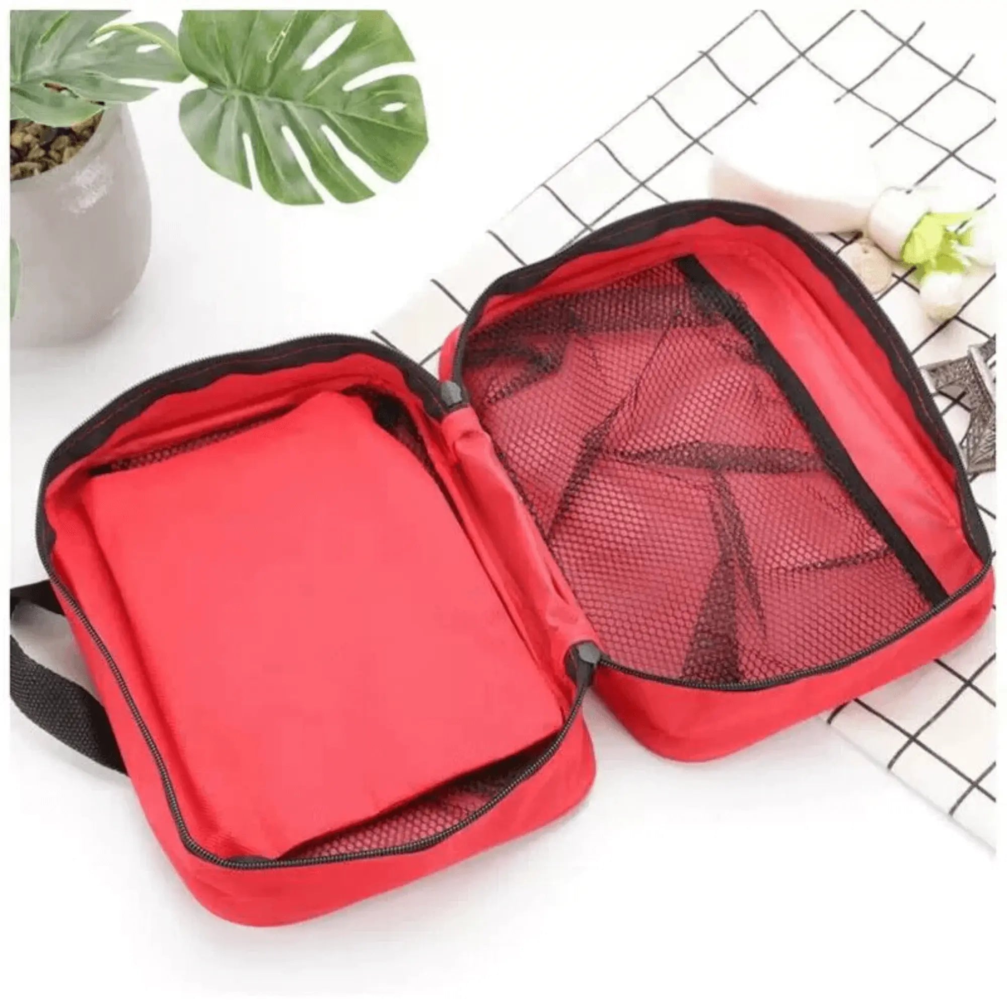 Trousse de secours d’urgence rouge ouverte avec compartiments en filet, parfaite pour le camping, les voyages et les randonnées.
