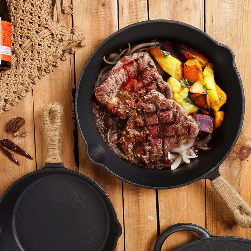 Poêle en fonte de 26cm avec steak et légumes, idéale pour cuisine camping sur réchaud ou feu de camp, goût authentique et livraison groupée.