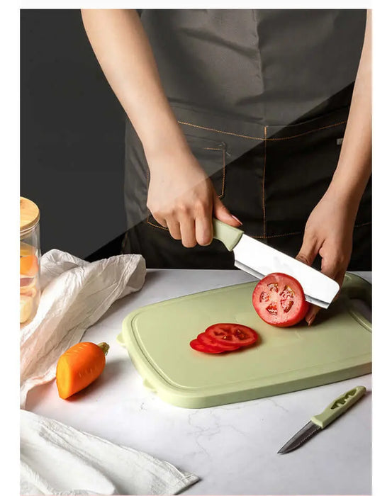 Une personne tranchant une tomate sur une planche à découper pliante en silicone verte, mettant en avant le mandoline de cuisine 9 en 1, parfait pour le camping.