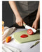 Une personne tranchant une tomate sur une planche à découper pliante en silicone verte, mettant en avant le mandoline de cuisine 9 en 1, parfait pour le camping.