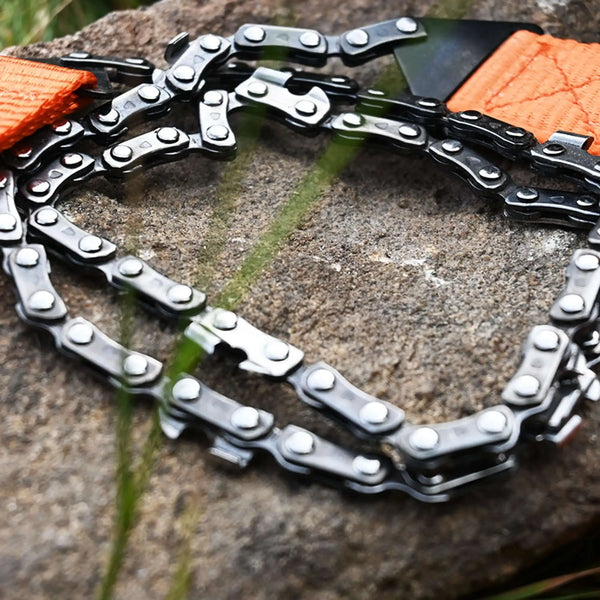 Tronçonneuse / Scie manuelle de camping avec poignées orange sur une pierre, idéale pour découpe rapide et sans ampoules.