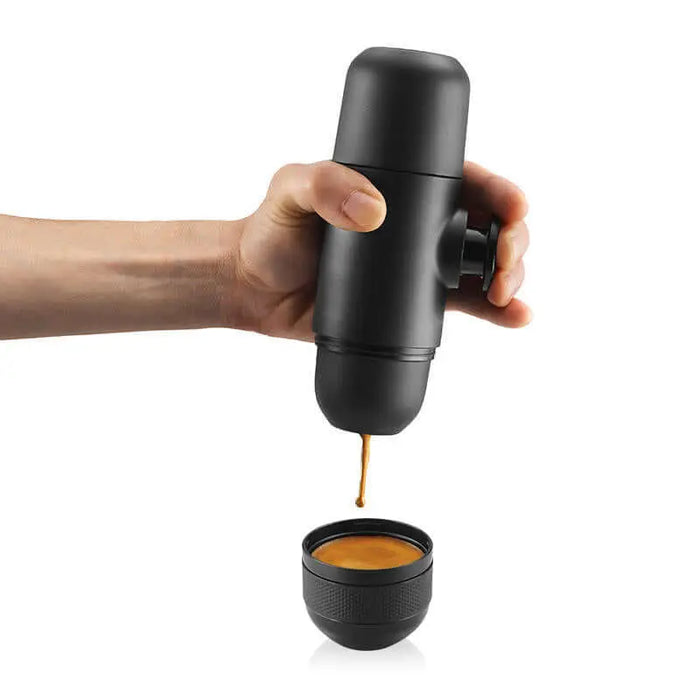 Machine à expresso Nespresso portable délivrant du café dans une tasse, idéale pour le camping et les amateurs de plein air.