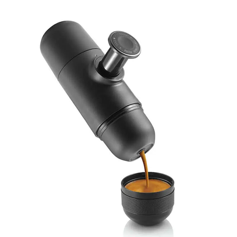Portable espresso machine brewing coffee into a cup, ideal for camping and outdoor use, lightweight and easy to operate.