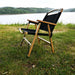 Chaise de camping pliante en bois noir au bord d'un lac, parfaite pour la détente en plein air, dotée d'un siège en tissu Oxford 600D durable.