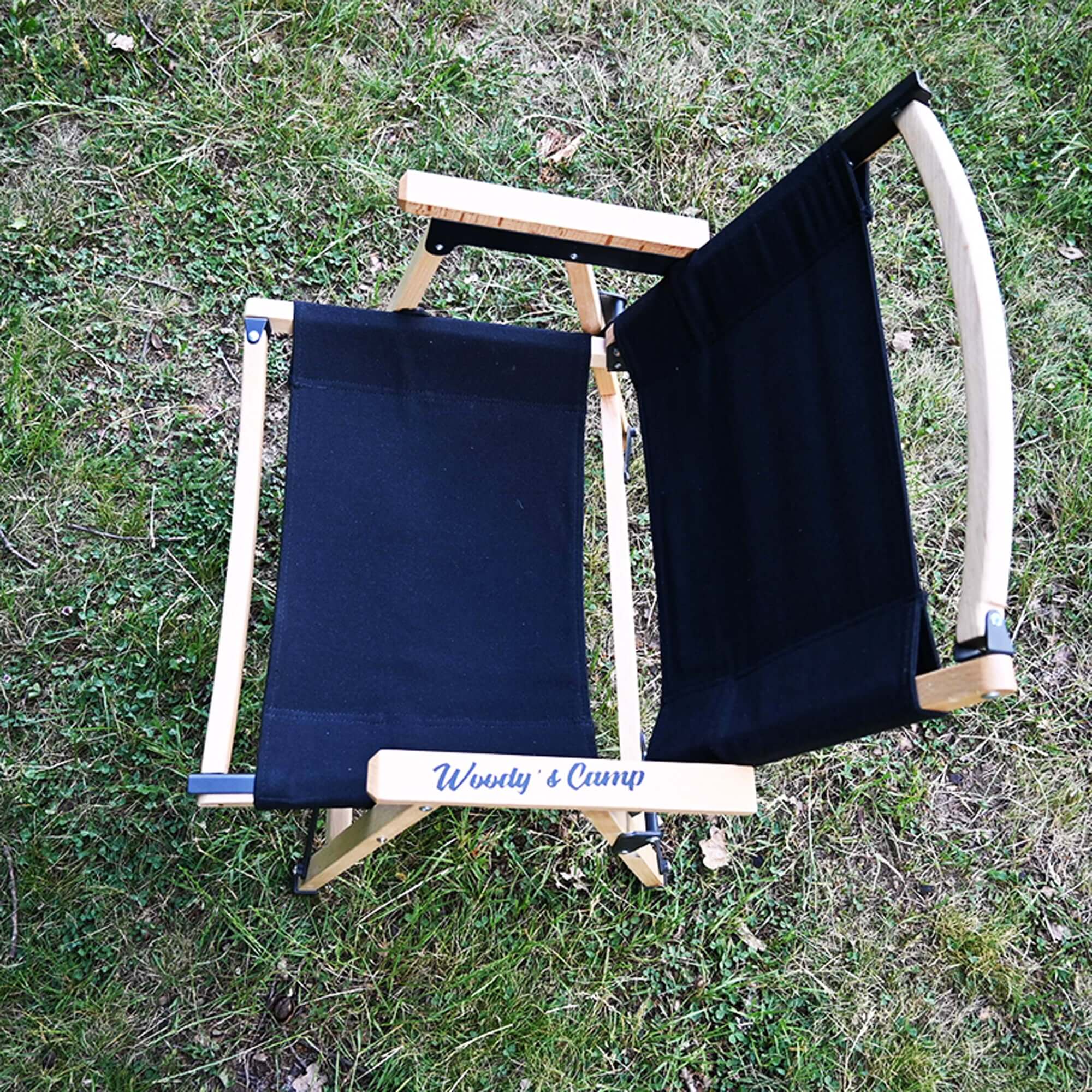 Chaise de camping pliante en bois noire avec tissu Oxford 600D résistante, vue de dessus sur pelouse verte.