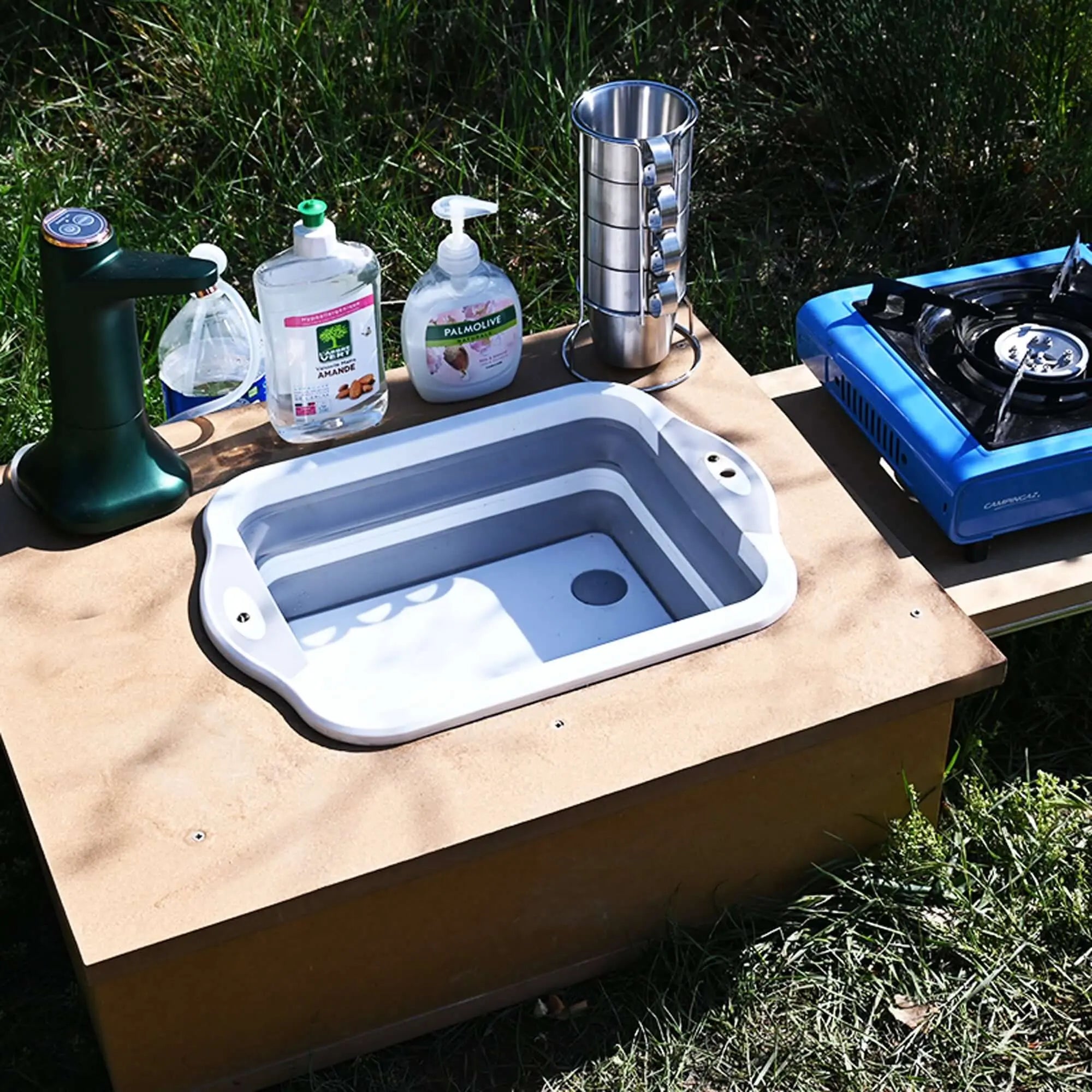 Camping electric faucet with USB charging, set up on outdoor sink with stove. Ideal for van, caravan, or kitchen use.