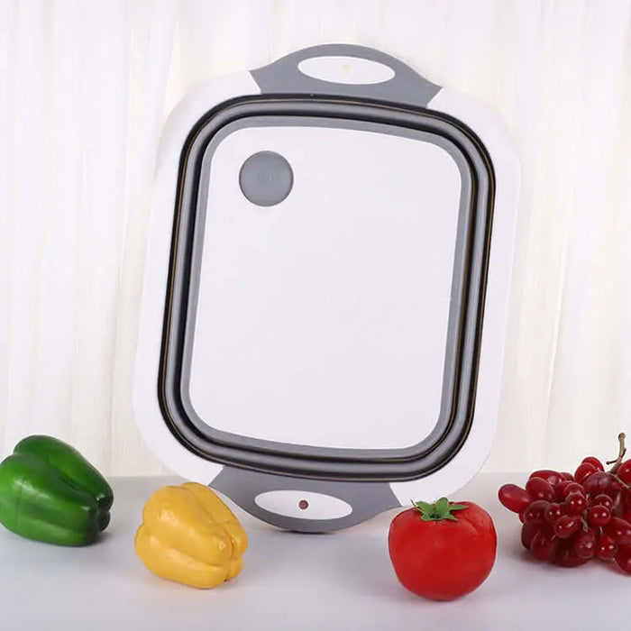 Évier pliable en silicone avec planche à découper portable pour le camping, entouré de légumes colorés.