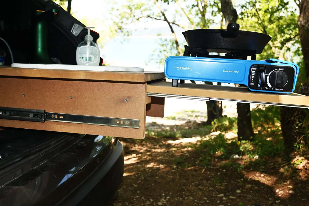 Réchaud de camping et ustensiles de cuisine sur un tiroir coulissant extensible avec glissières à billes dans un environnement forestier.
