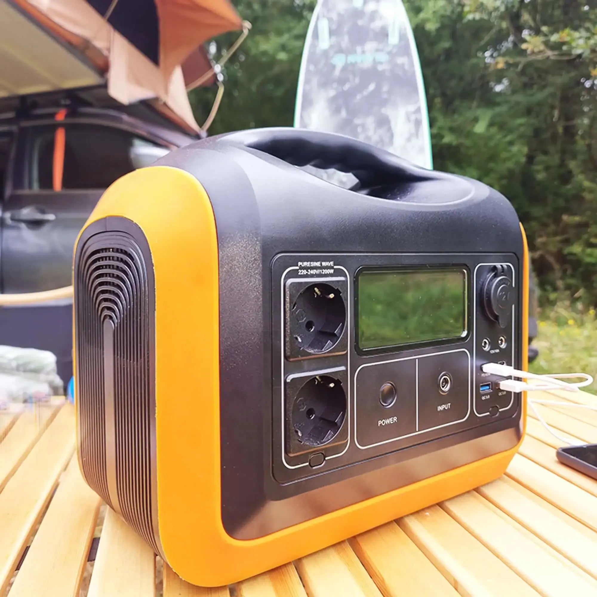 Portable battery pack on a wooden table outdoors, ideal for travel and powering devices in remote locations.
