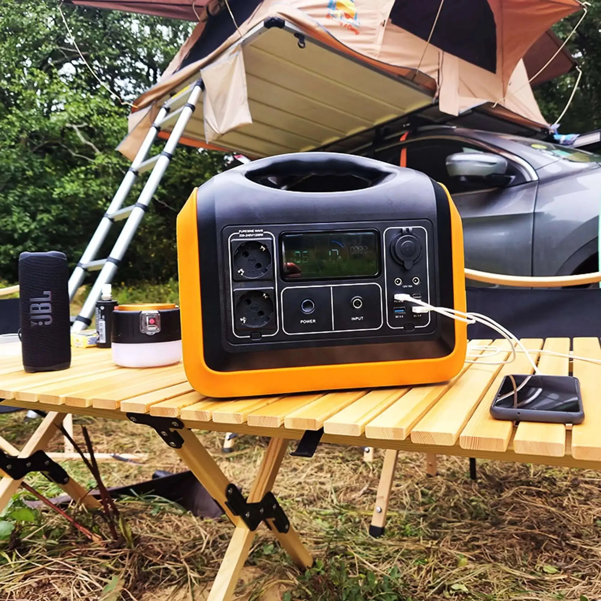 Portable power station with solar panels on a camping table, showcasing outdoor use for charging devices.