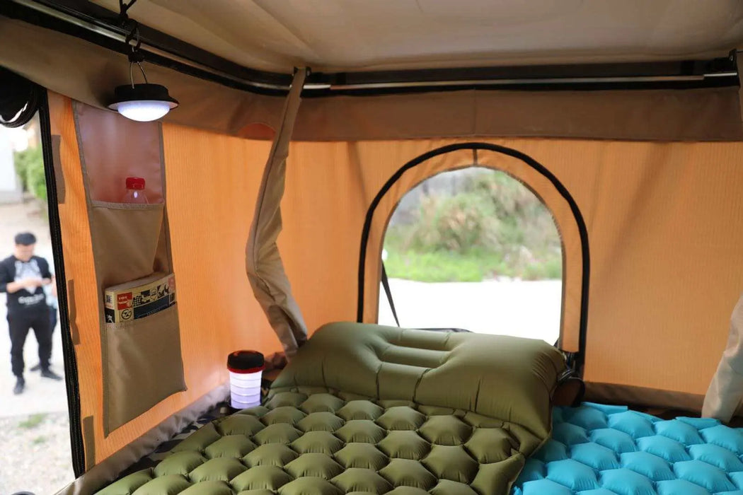 Intérieur d'une tente de toit avec un matelas de camping gonflable, murs beiges et vue sur l'extérieur.
