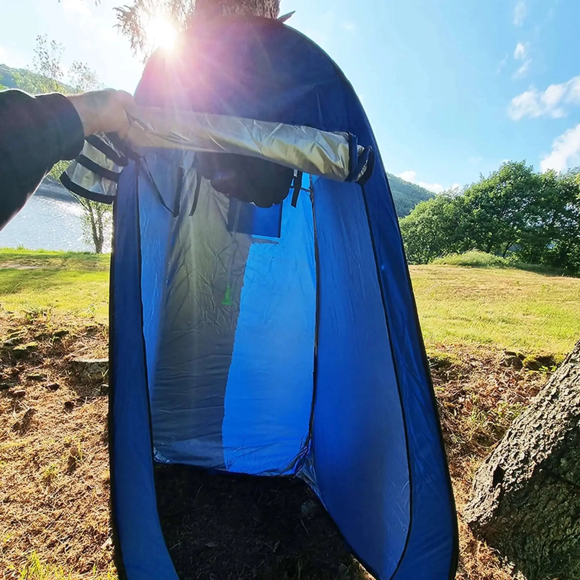 Tente de douche camping pliable en plein air installée au bord d'un lac, idéale pour le camping sauvage et les aventures en nature.