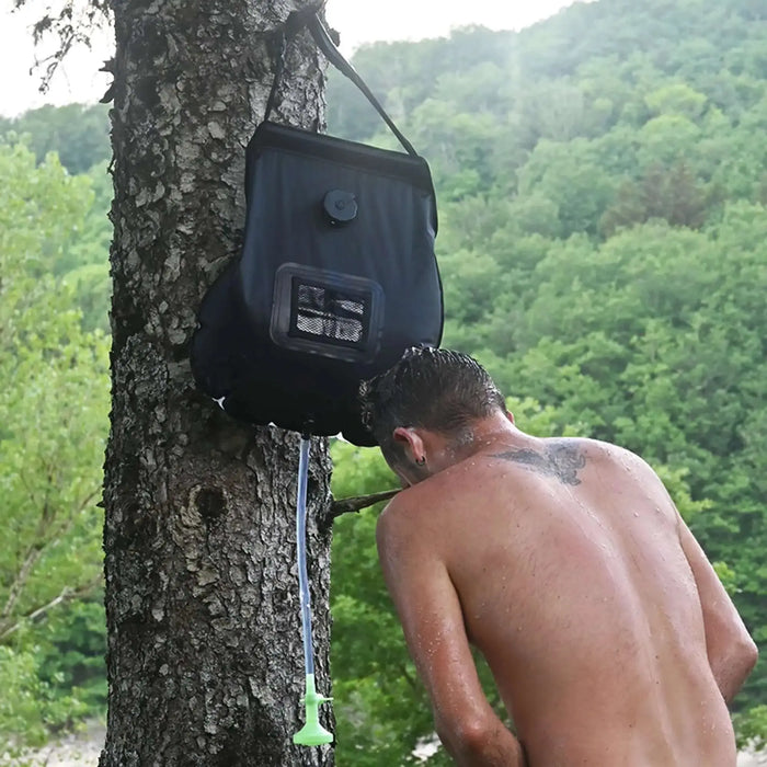 Homme utilisant un sac de douche solaire de 20L en extérieur, idéal pour le camping, la randonnée et les aventures écologiques.