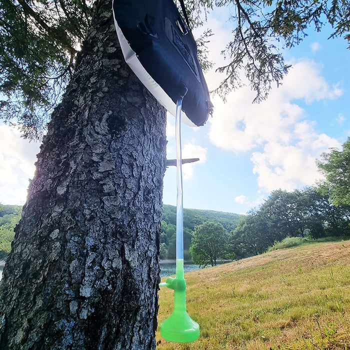 Sac de douche solaire portable de 20L suspendu à un arbre, idéal pour les activités en plein air comme la randonnée et la pêche.