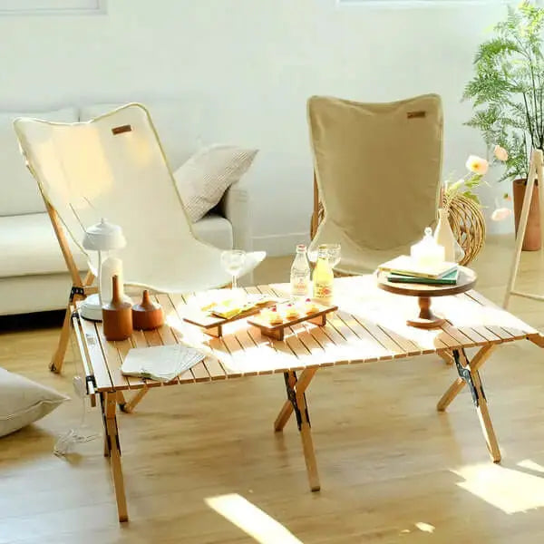 Table en bois pliable pour camping avec accessoires, idéale pour pique-niques en extérieur, montrée avec chaises et décorations.