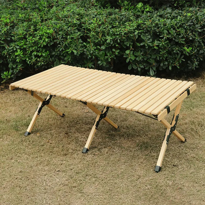 Table de camping en bois pliable installée en plein air, avec des charnières durables pour un rangement facile.