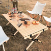 louer materiel camping table chaise montpellier location herault 34000 woodys camp Table de camping en bois pliable installée en extérieur avec des chaises, des boissons et de la nourriture, mettant en avant un design durable pour des repas confortables en plein air.