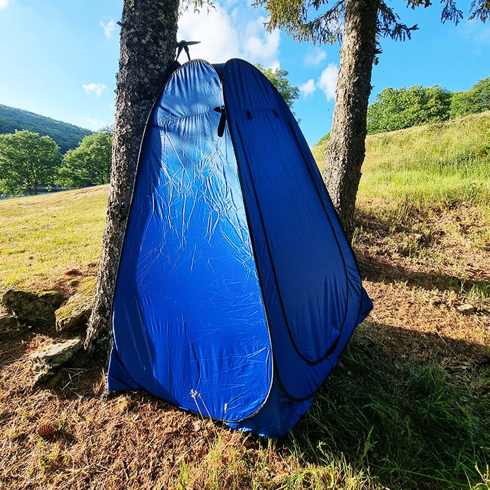 Blue foldable outdoor camping shower tent set up in a forest, offering privacy for showers, changing, and more during adventures.