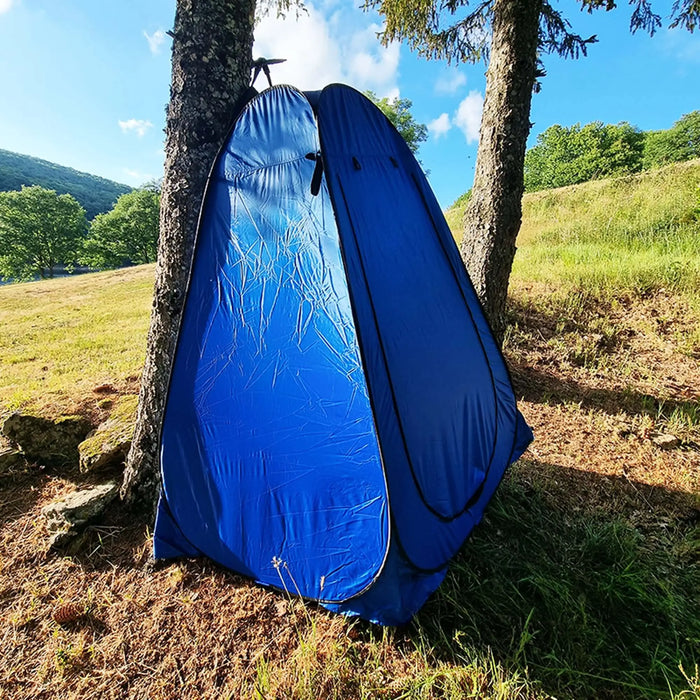 Tente de douche extérieure pliante bleue installée dans une forêt, offrant de l'intimité pour prendre des douches, se changer et plus encore lors des aventures.