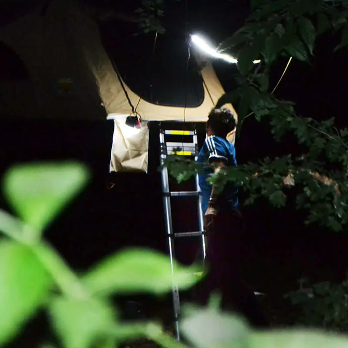 Campeur utilisant une bande LED flexible de 72 pour éclairer la tente de toit la nuit.